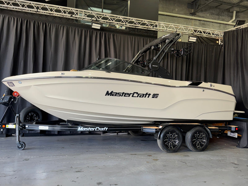 2026 MasterCraft XT22T - Stone hull side profile on trailer against black showroom curtains