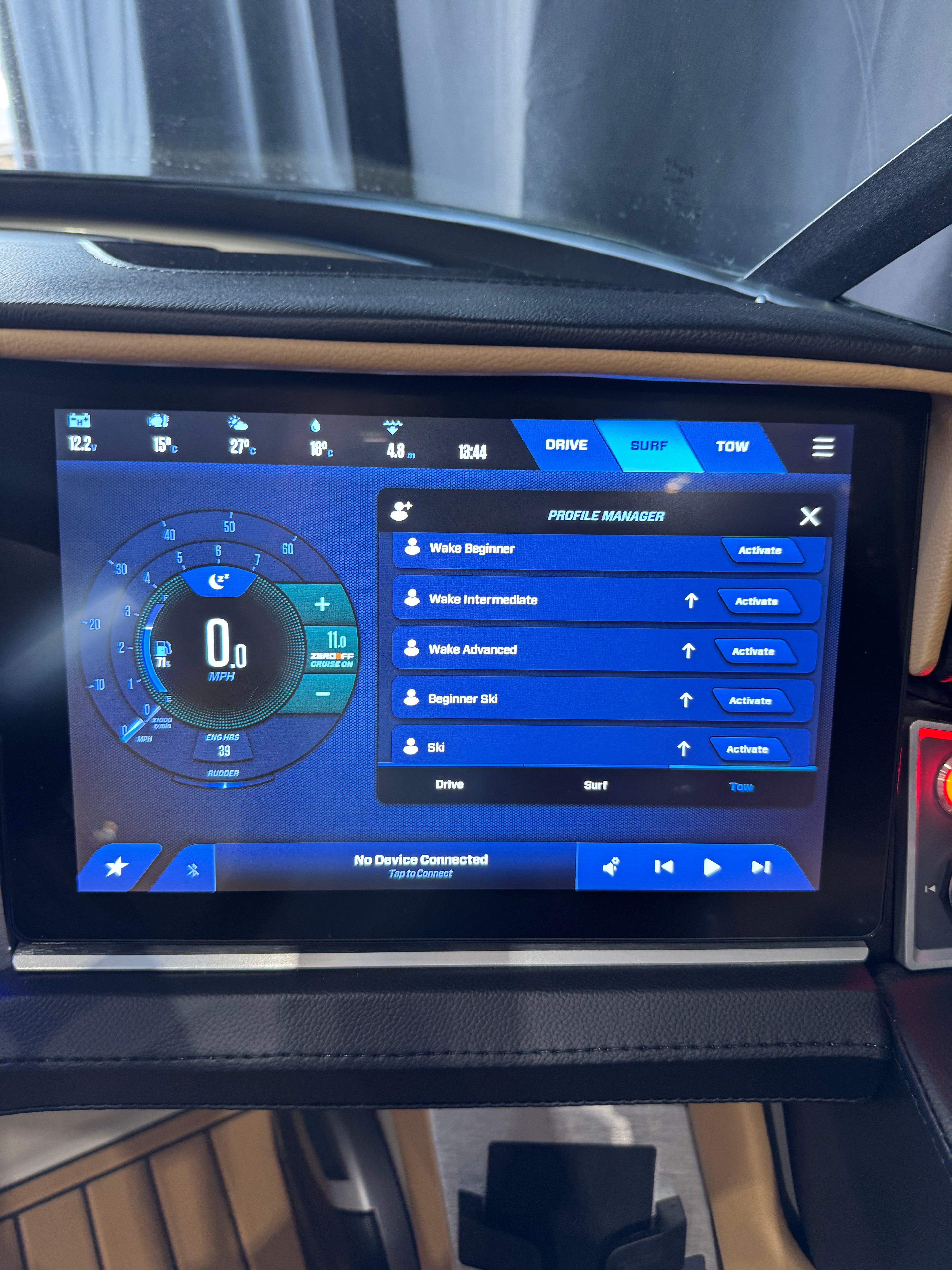 A close-up of a MasterCraft XT22T  large touchscreen display mounted on a vehicle dashboard, showing a blue and black user interface with drive profile options and a circular gauge graphic.