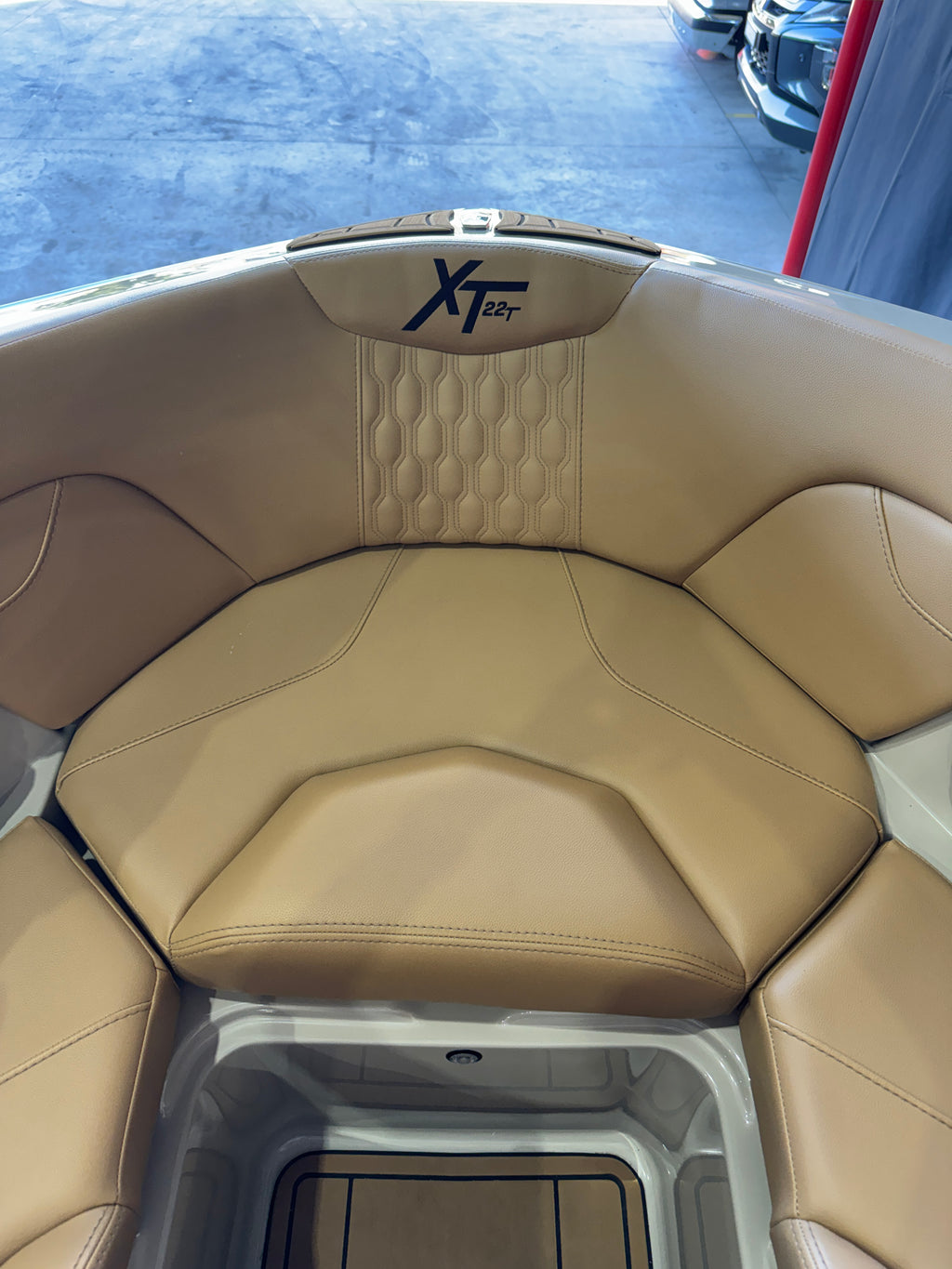 Close-up of a tan leather boat seat with a quilted backrest and an MasterCraft XT22T logo embroidered in black on the headrest area.