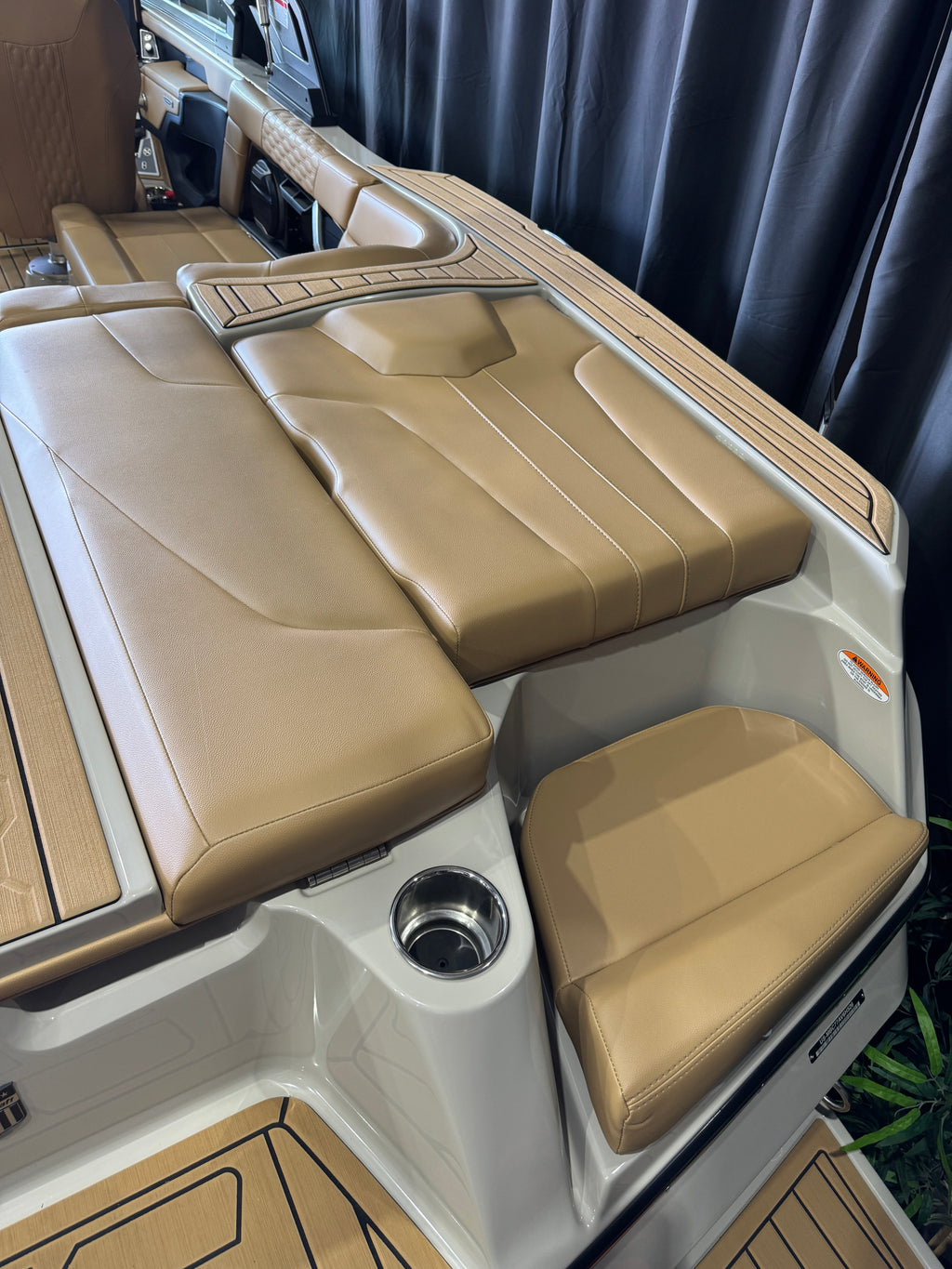 Beige upholstered MasterCraft XT22T  boat seating with wood-look trim and a white console base, photographed in a boat interior or showroom setting.