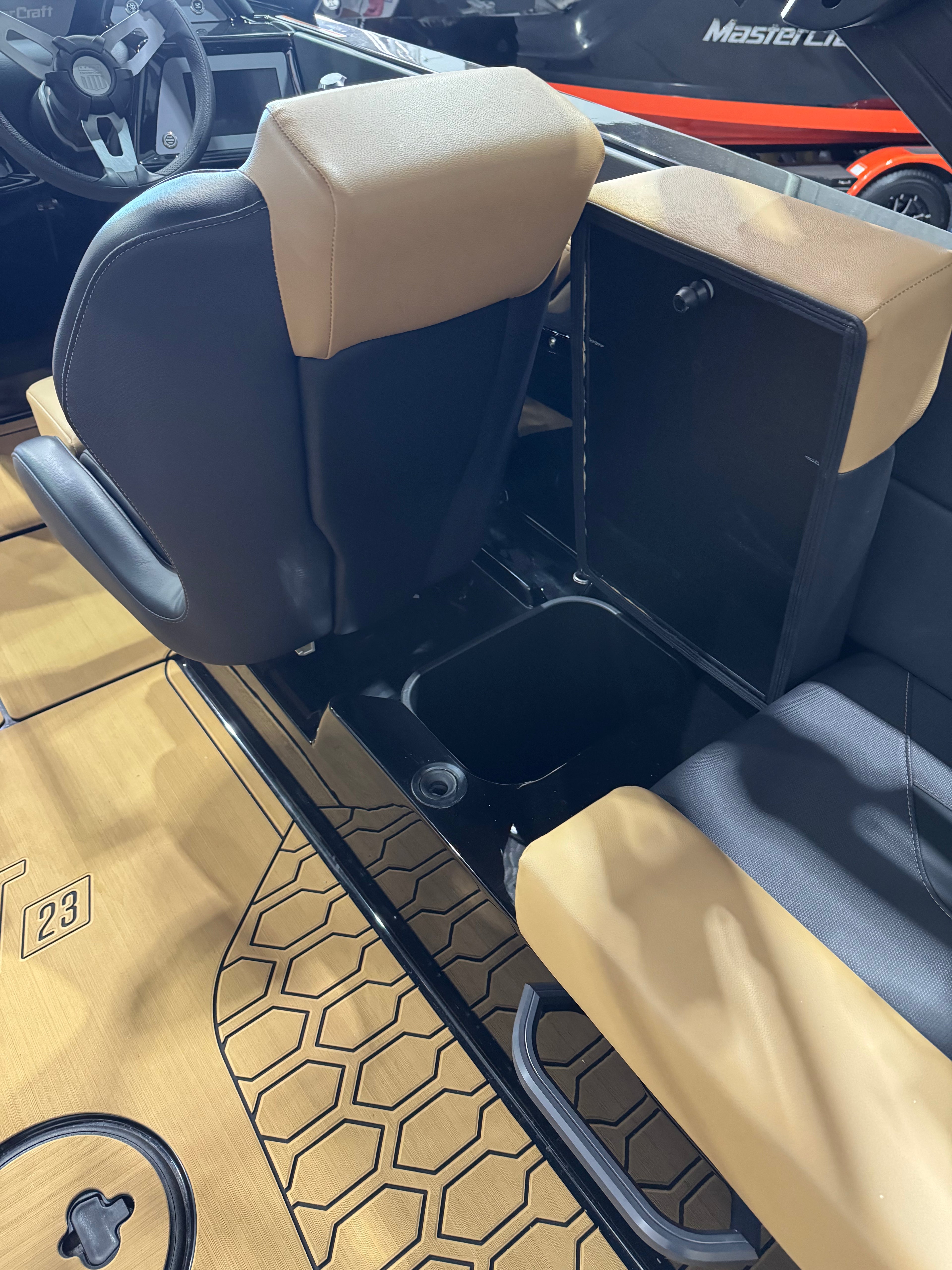 Tan and black boat cabin seats with a storage compartment and wood-look flooring, photographed inside a boat.